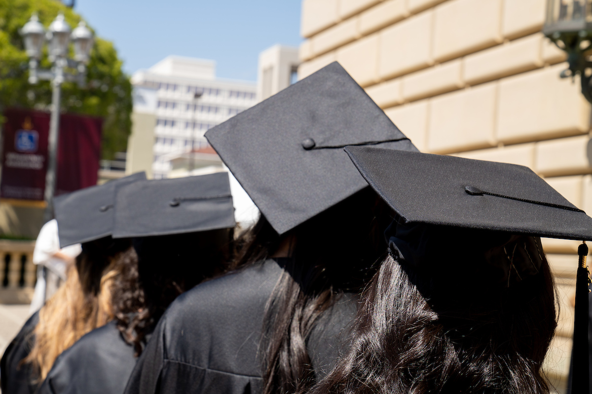 A group of women in graduation hats walking down a street.