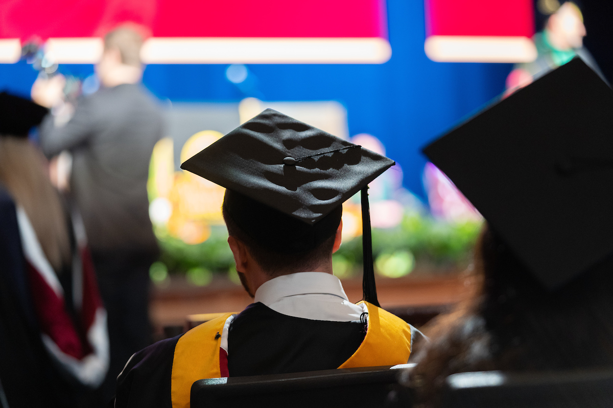 A graduate wearing a cap and gown at a graduation ceremony.