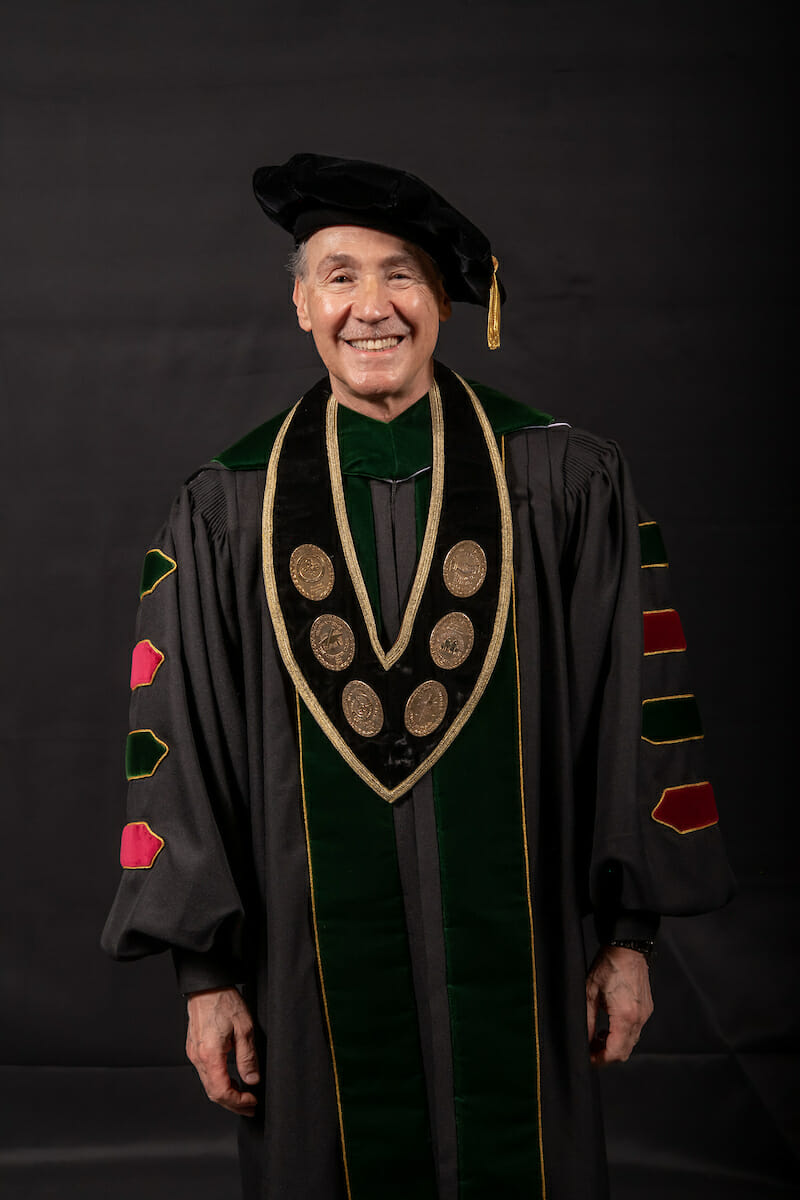 President Robin Farias-Eisner in a graduation gown smiling.
