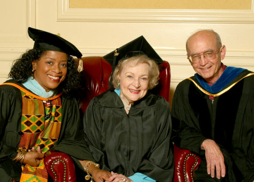 Three people in graduation robes posing for a photo.
