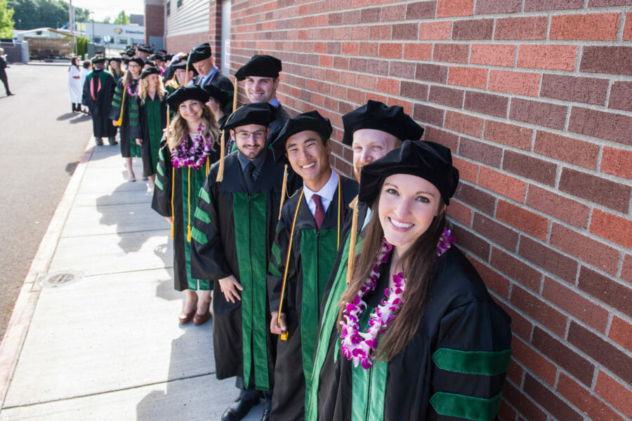 A group of graduates standing in front of a brick wall.