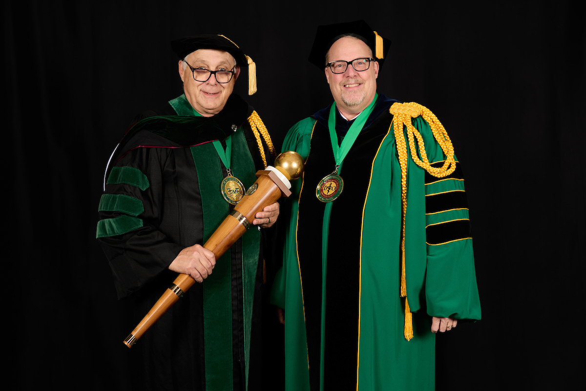 Two men in green robes posing for a photo.