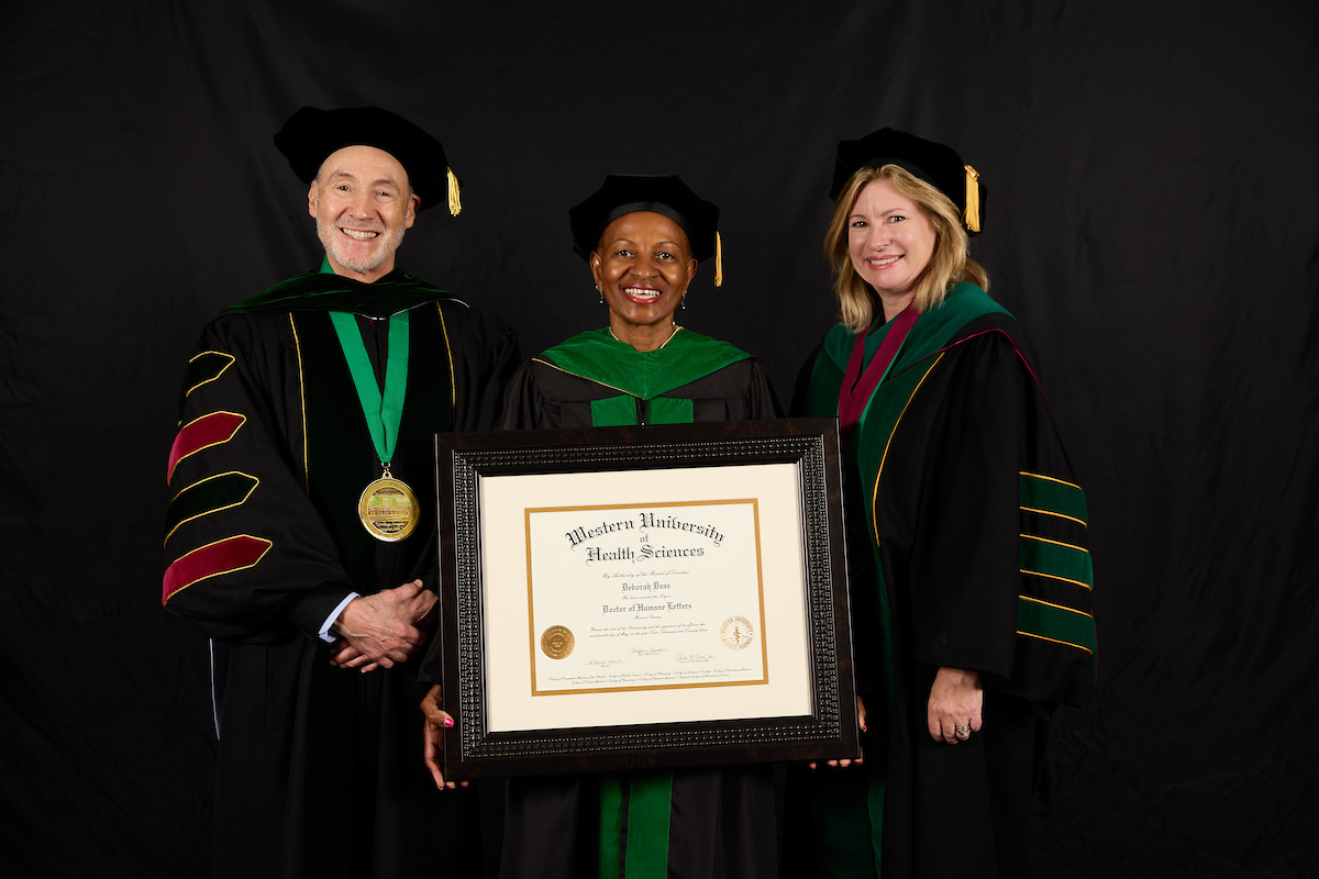 Three people in robes posing for a photo with a certificate.