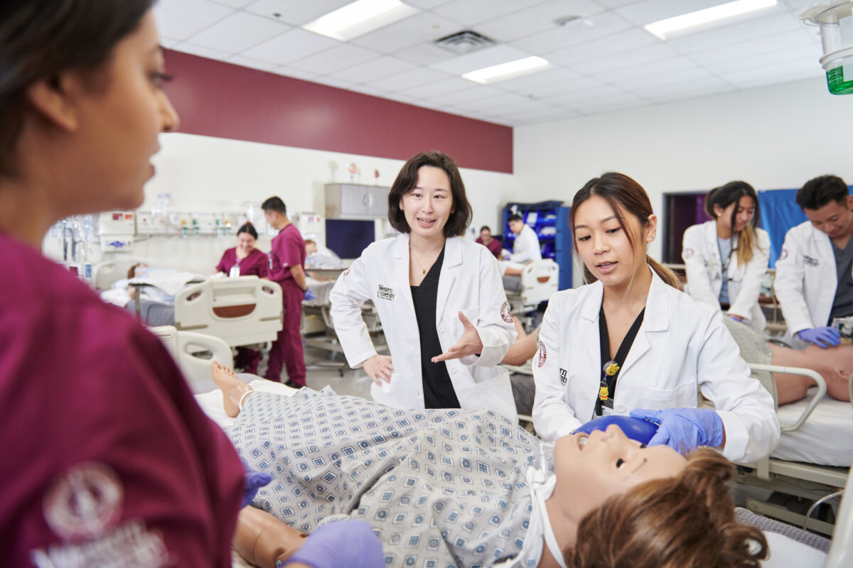 A group of medical students in a room with a mannequin.