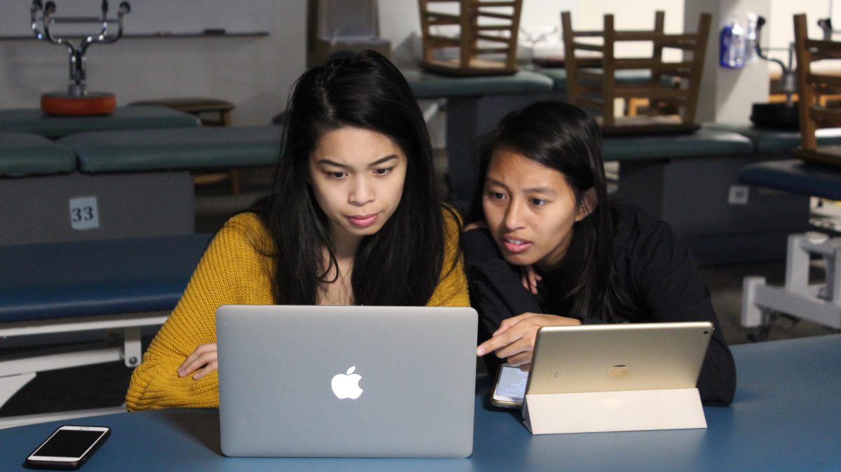 A couple of students looking at an Apple MacBook