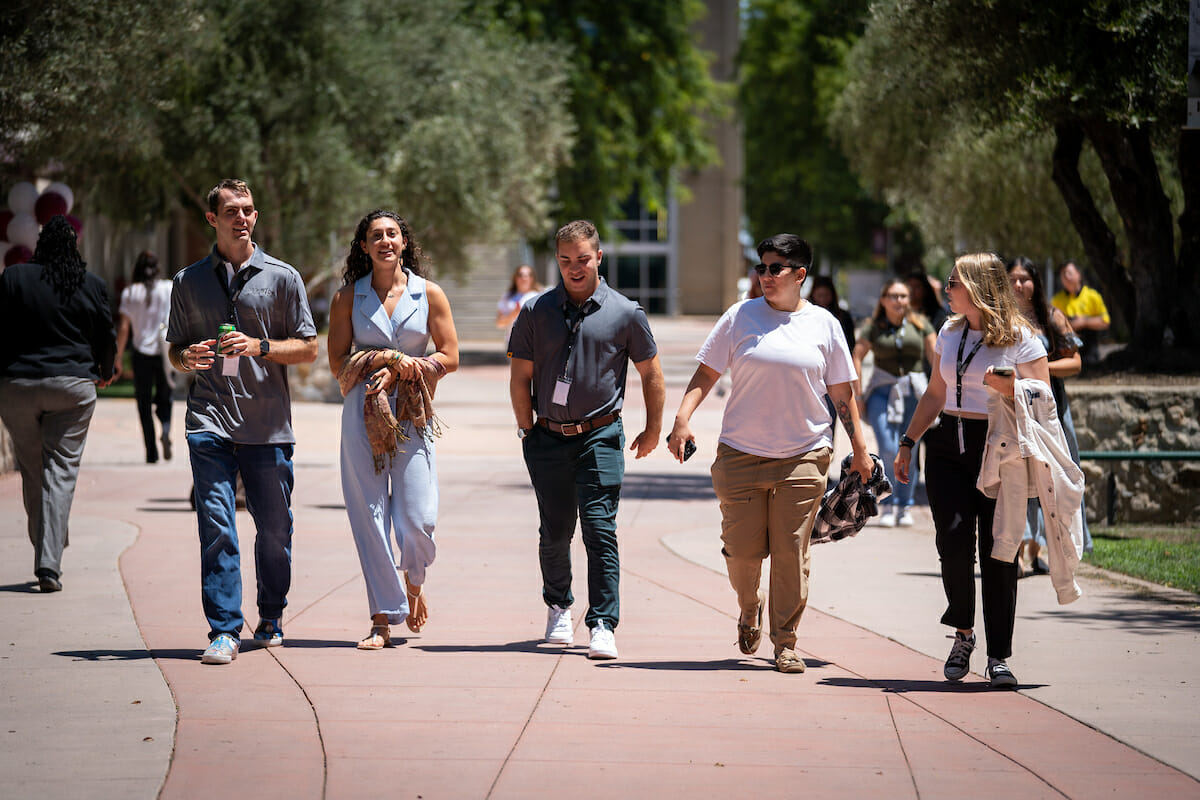 A group of people walking down a sidewalk.