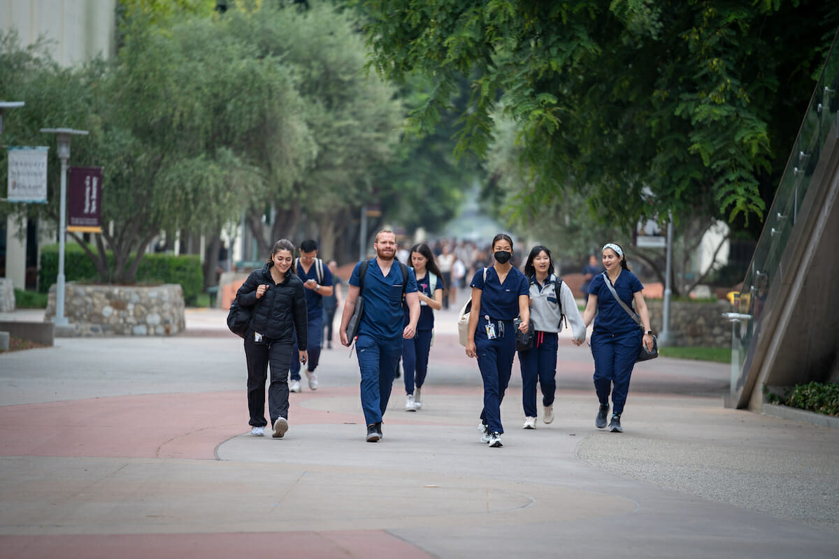 A group of medical students walking down a sidewalk.