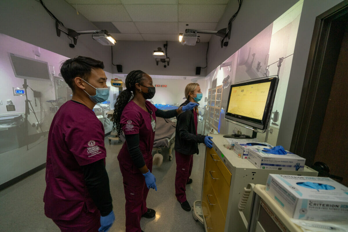 Nursing students looking at monitor in simulation suite.