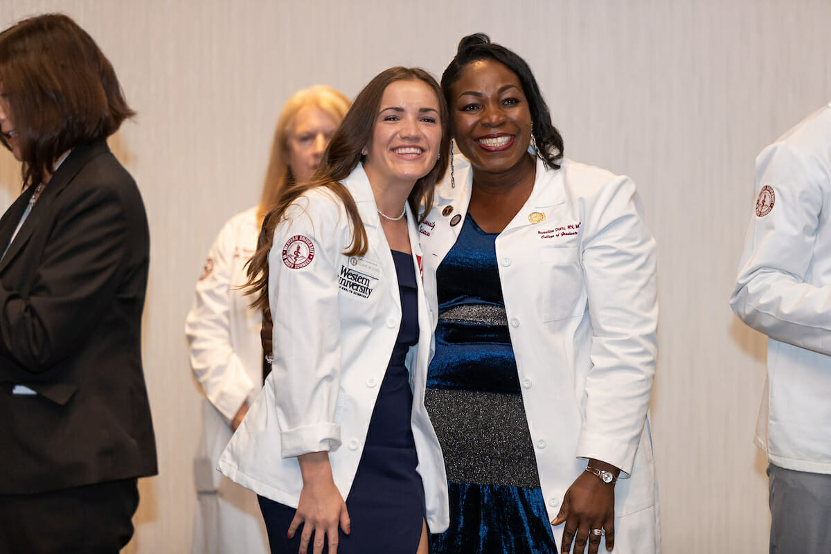 two students are standing on CGN MSNE Pinning Ceremony