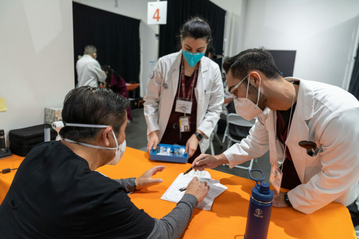 Two students in white coat working at care harbor