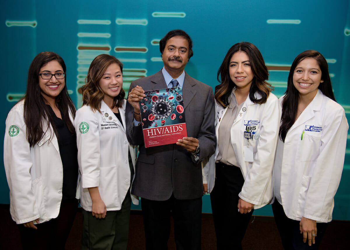 College of Osteopathic Medicine of the Pacific (COMP) Associate Professor Vishwanath Venketaraman, PhD, shows off a textbook featuring collaborative efforts with COMP students from left, Parveen Hussain, Judy Ly, Leslie Gonzalez and Alexis Alejandre