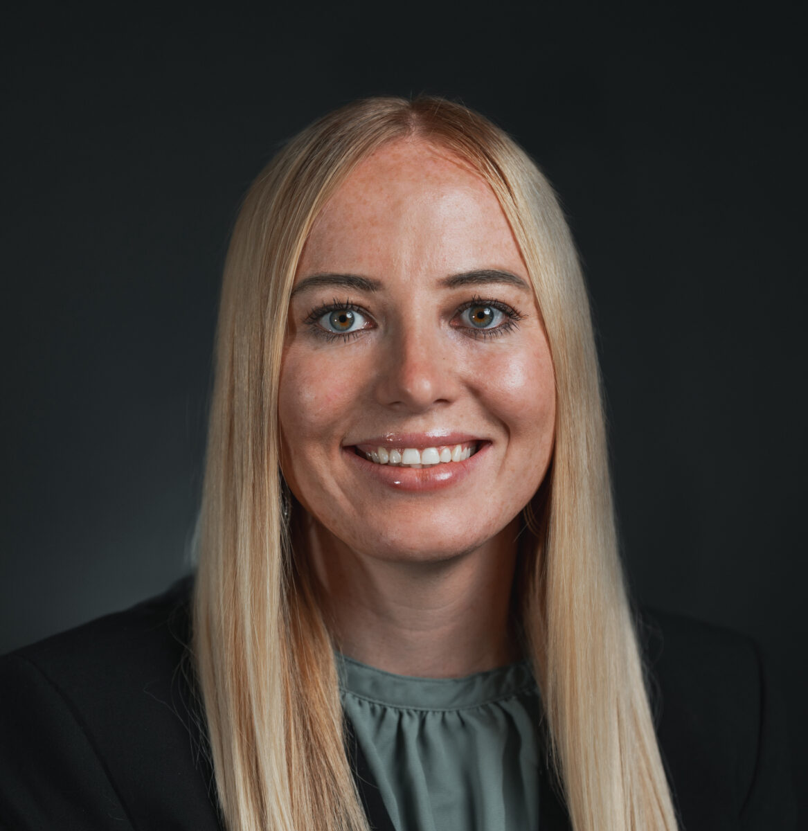 A woman in a business suit smiling for the camera.