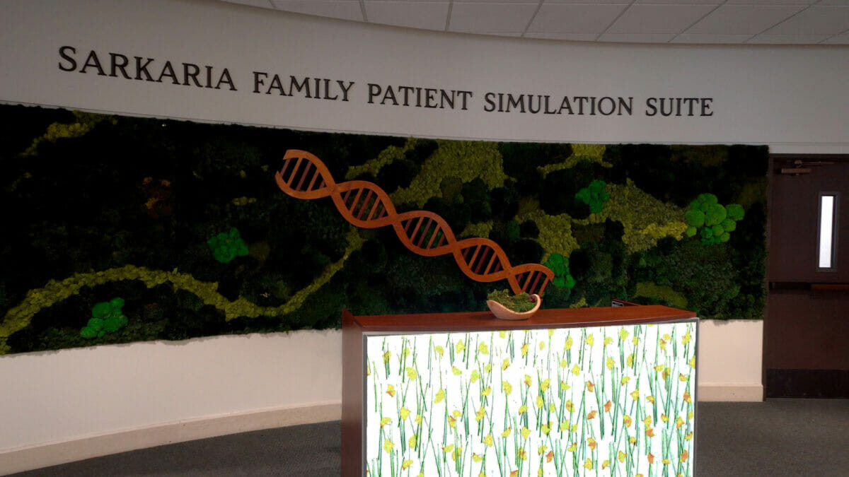 A green wall with a sign that says sarkar family patient simulation suite.