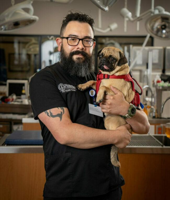 RVT Nicholas Garcia holding his pet dog in the PHC with medical equipment in the background.