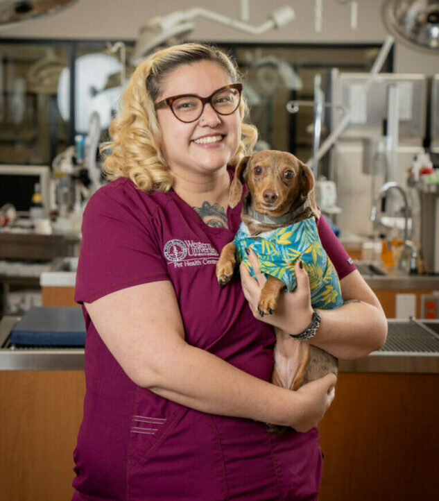 RVT Marisol Haro holding her pet dog in the PHC with medical equipment in the background.