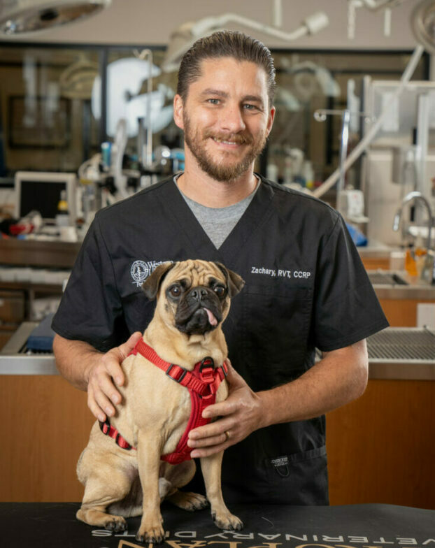 RVT Zachary Morris with his pet dog in the PHC with medical equipment in the background.