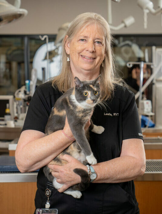 RVT Leslie Tortez holding her pet cat in the PHC with medical equipment in the background.