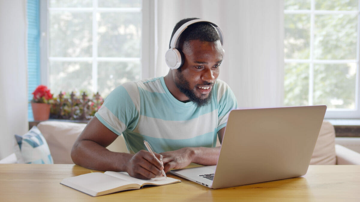 Image of student studying on laptop and writing in notebook