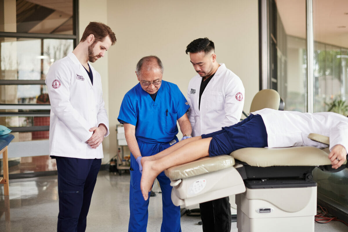 Podiatric Medicine student attending a man on a table.