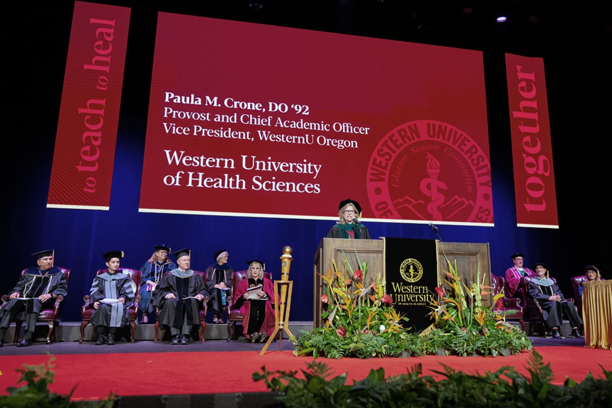 Dr. Crone speaking on stage at a commencement ceremony.