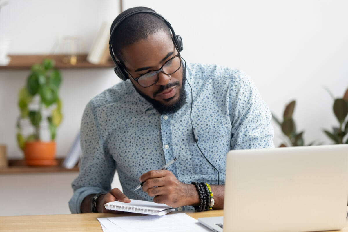 Image of a student wearing headphones and taking notes