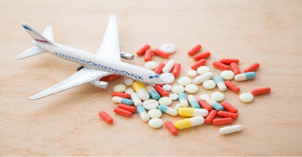 A toy airplane and pills on a wooden table.