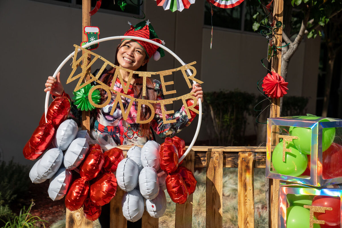 A woman standing in front of a christmas wreath and balloons at Winter Wonder Fest, California campus, Nov. 2023.