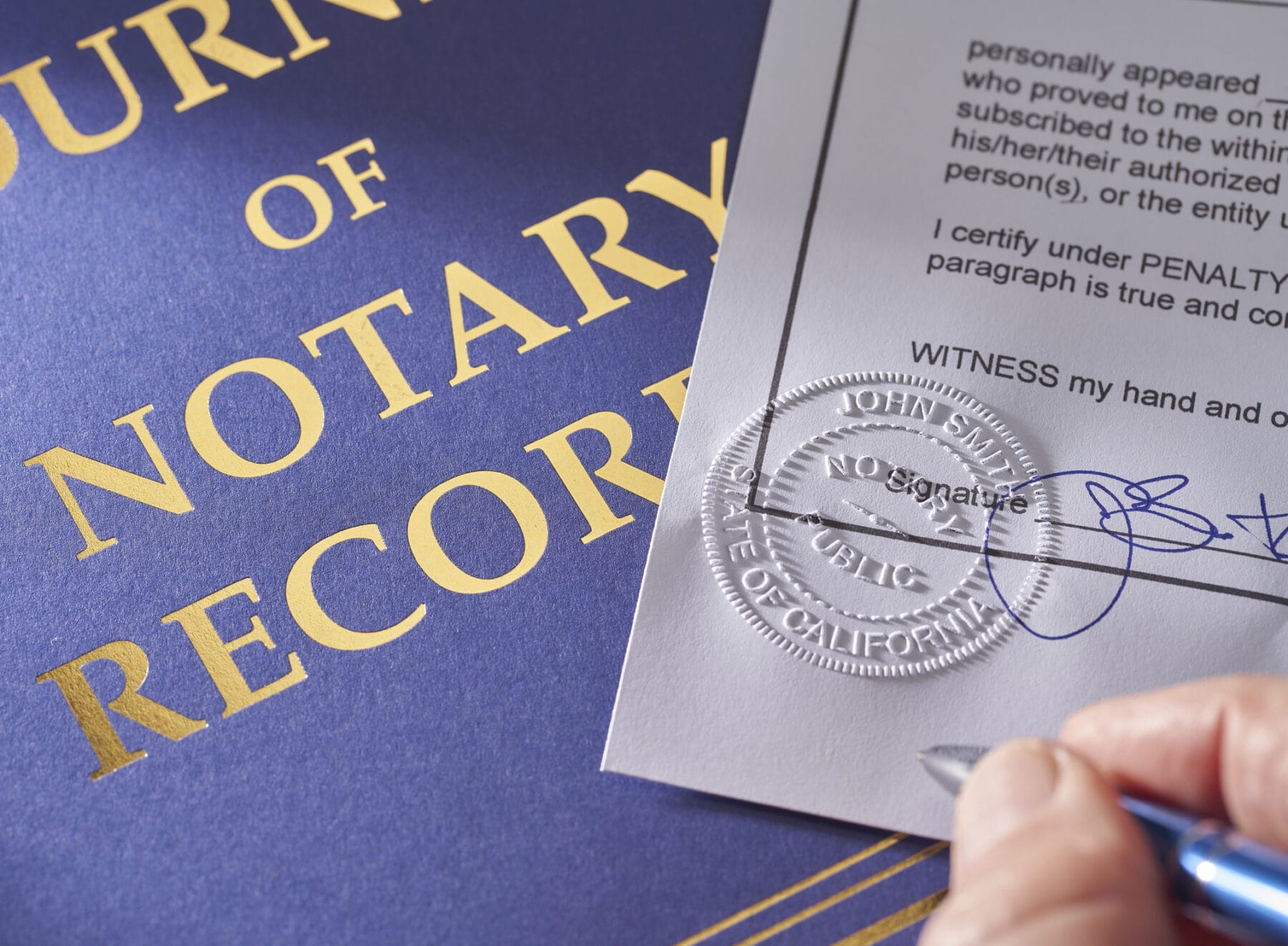 A person signs a document next to an embossed notary seal with a Journal of Notary Records in the background.