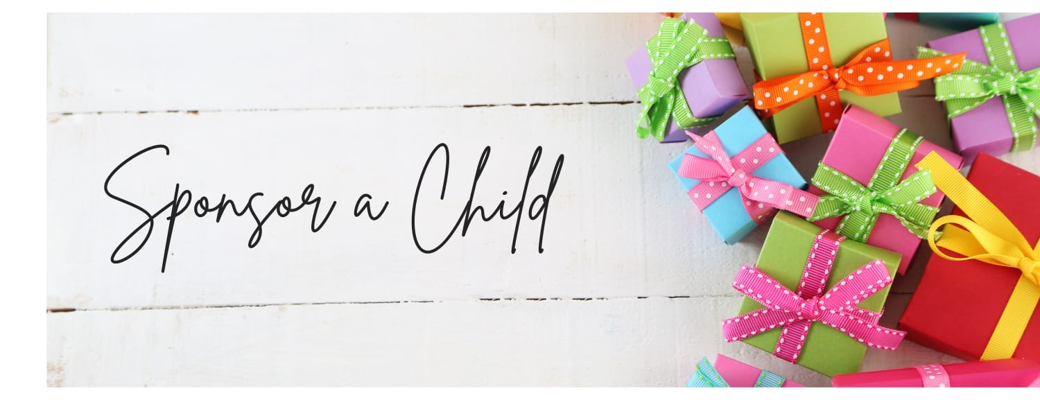 Colorful gift boxes with ribbons are arranged on a white wooden surface next to the text "Sponsor a Child.