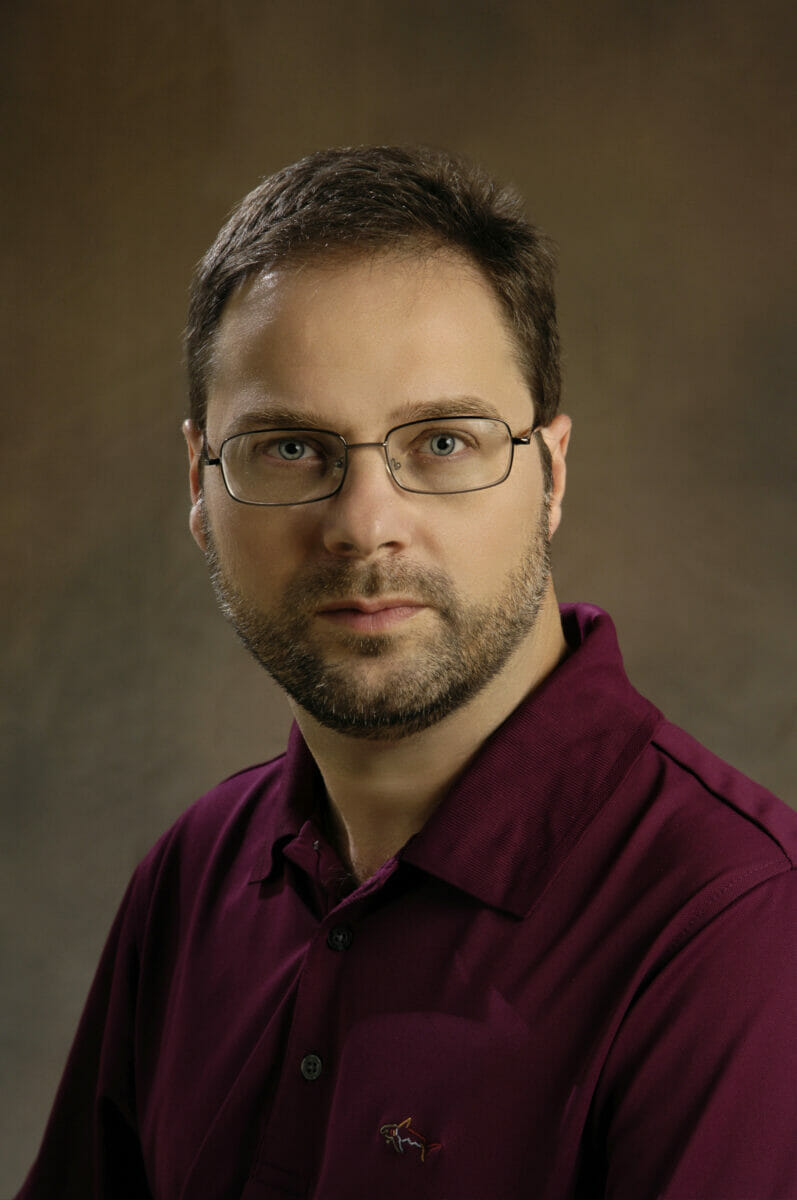 a man wearing glasses and a maroon shirt.